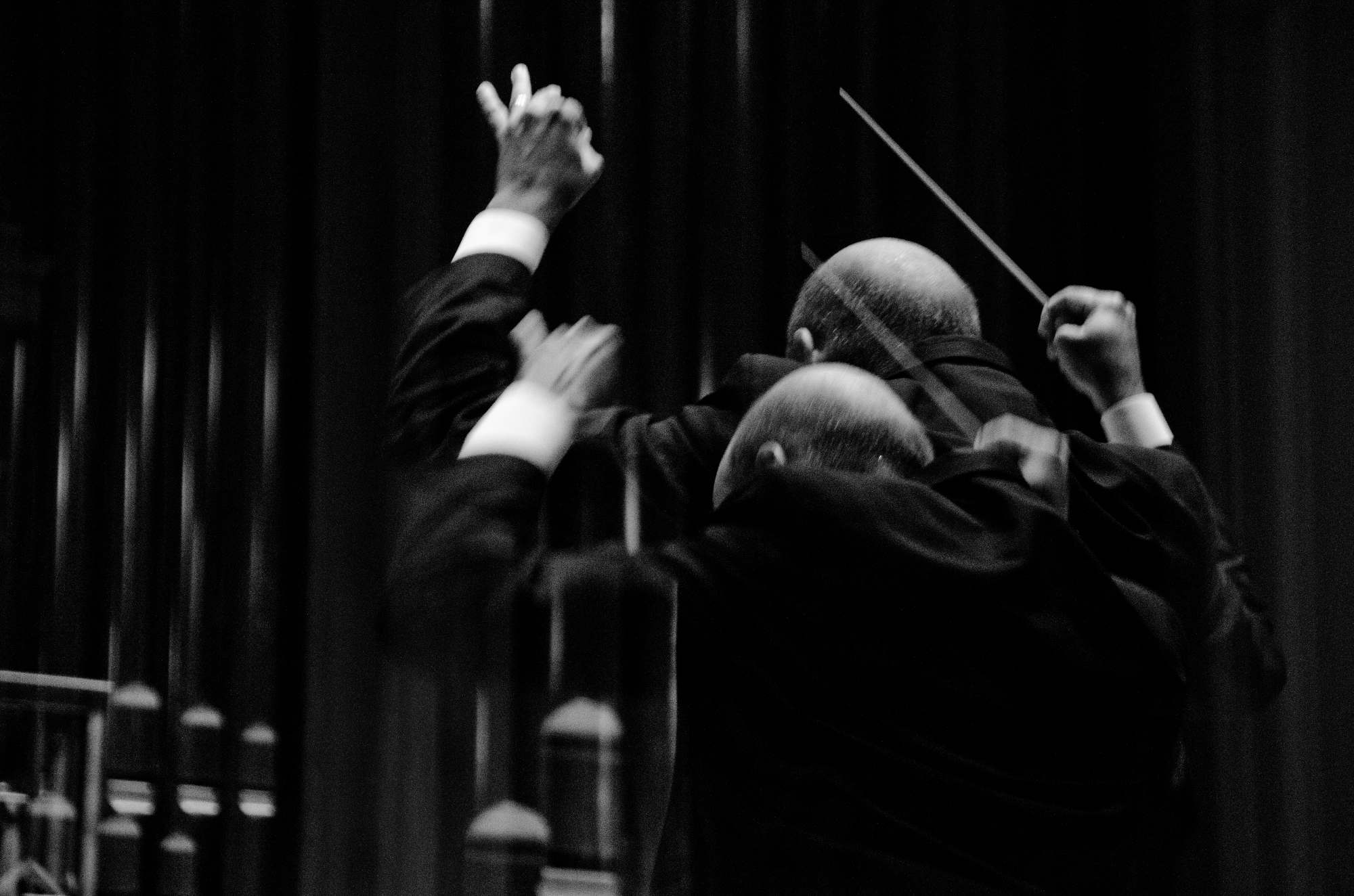 A double exposure photograph of an orchestral conductor at work.